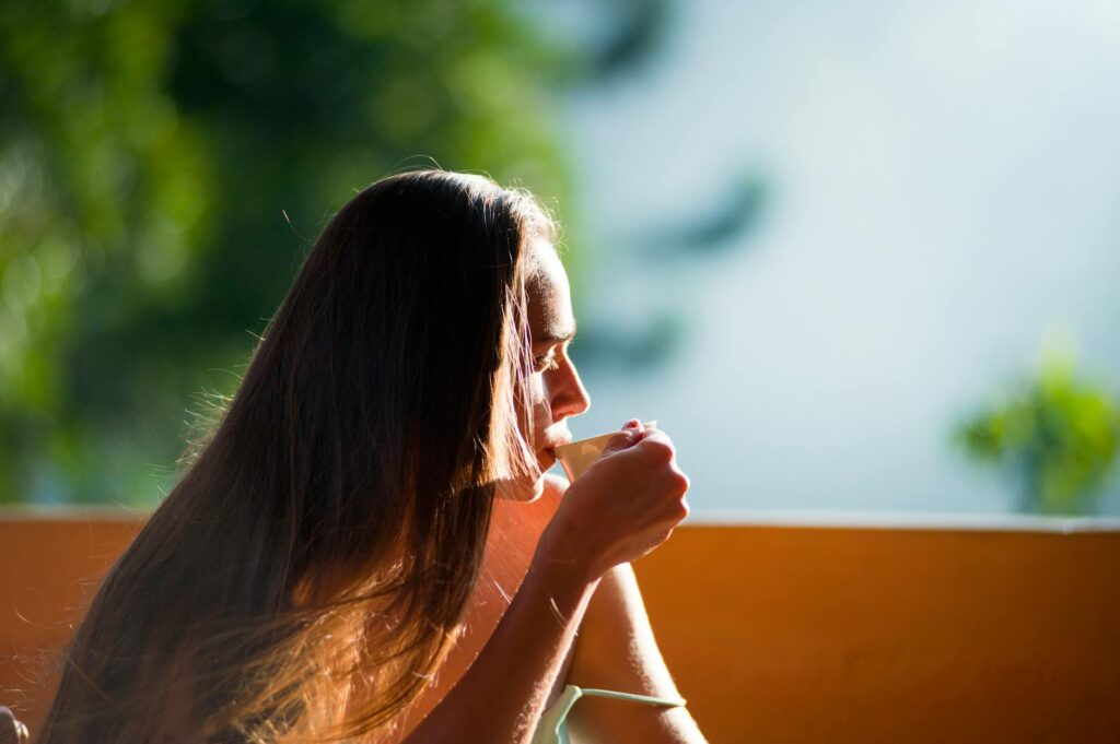 Frau sitzt nachdenklich am Fenster und schaut in die Natur, Achtsamkeit und innere Ruhe im Alltag