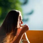Frau sitzt nachdenklich am Fenster und schaut in die Natur, Achtsamkeit und innere Ruhe im Alltag