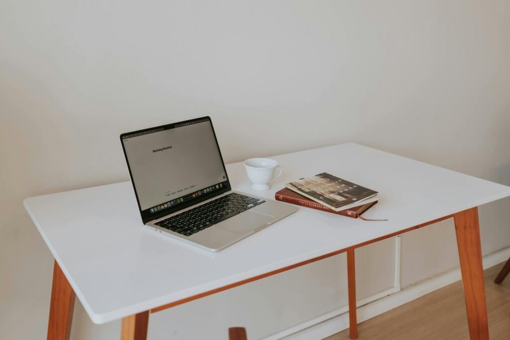 Aufgeräumter Schreibtisch mit Laptop, Kaffeetasse und Büchern symbolisiert strukturiertes Homeoffice und Work-Life-Balance