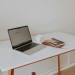 Aufgeräumter Schreibtisch mit Laptop, Kaffeetasse und Büchern symbolisiert strukturiertes Homeoffice und Work-Life-Balance
